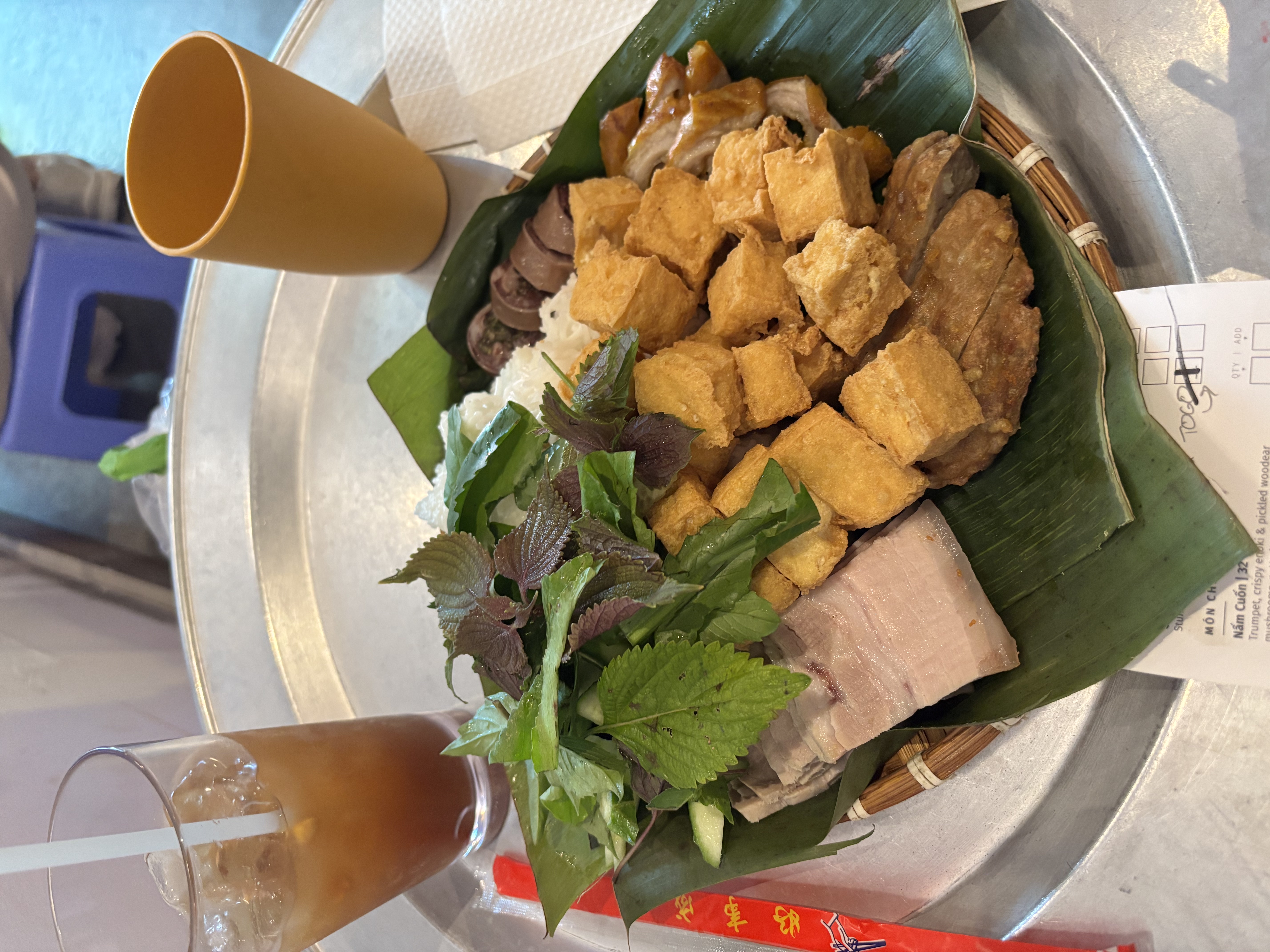 Plate of Bún Đậu Mắm Tôm over banana leaf and bamboo steamer.